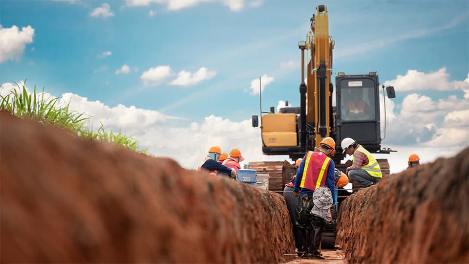 Workers using a machine to dig a trench